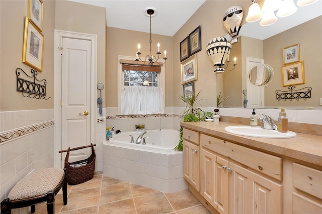 bathroom with tiled tub, an inviting chandelier, tile patterned flooring, tile walls, and vanity