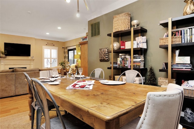 dining room featuring crown molding and light hardwood / wood-style floors