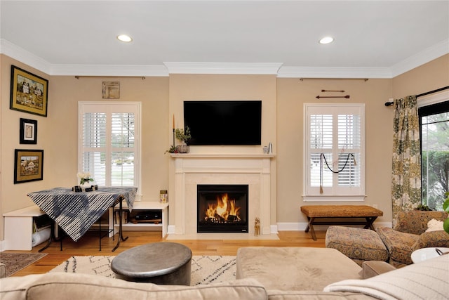 living room with a premium fireplace, ornamental molding, and light wood-type flooring