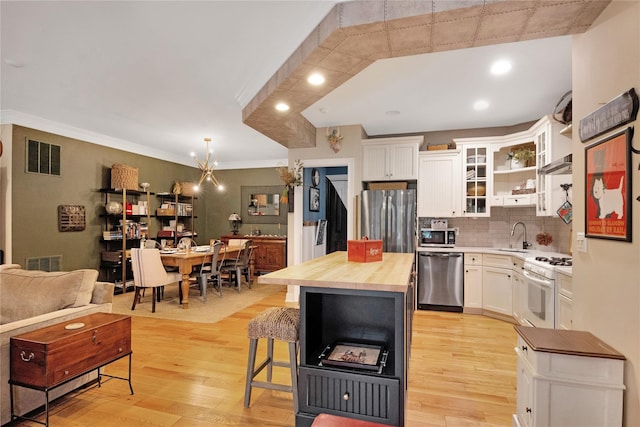 kitchen featuring butcher block countertops, a breakfast bar, appliances with stainless steel finishes, white cabinetry, and a center island