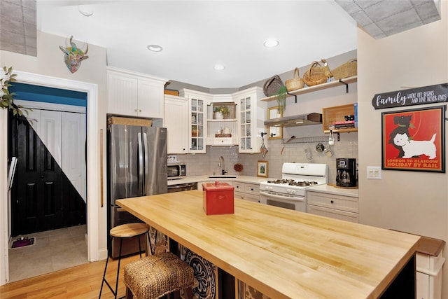 kitchen featuring sink, white cabinetry, backsplash, stainless steel appliances, and a kitchen bar