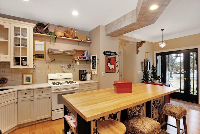 kitchen with pendant lighting, wood counters, white gas range, decorative backsplash, and light wood-type flooring