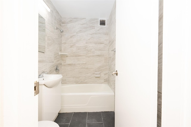 bathroom featuring toilet, tiled shower / bath combo, and tile patterned flooring