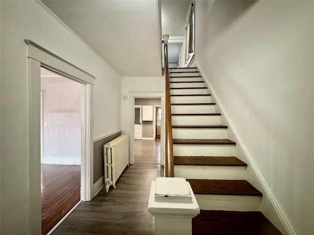 stairway featuring radiator and hardwood / wood-style floors