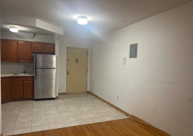 kitchen featuring sink, stainless steel fridge, light hardwood / wood-style floors, and electric panel