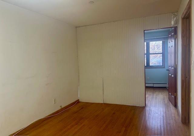 empty room featuring wood-type flooring and baseboard heating