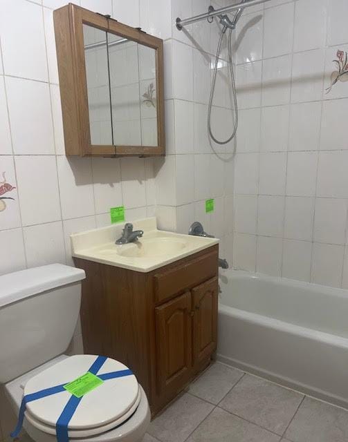 full bathroom featuring tiled shower / bath combo, vanity, tile walls, and toilet