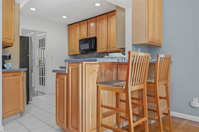 kitchen with light tile patterned floors and stainless steel refrigerator