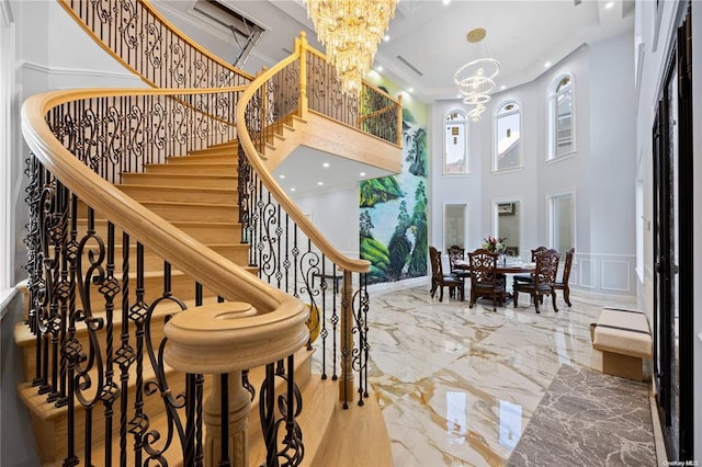 stairway with crown molding, a towering ceiling, and a notable chandelier