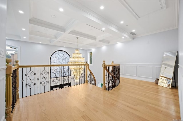 hallway with ornamental molding, coffered ceiling, a notable chandelier, light hardwood / wood-style floors, and beam ceiling