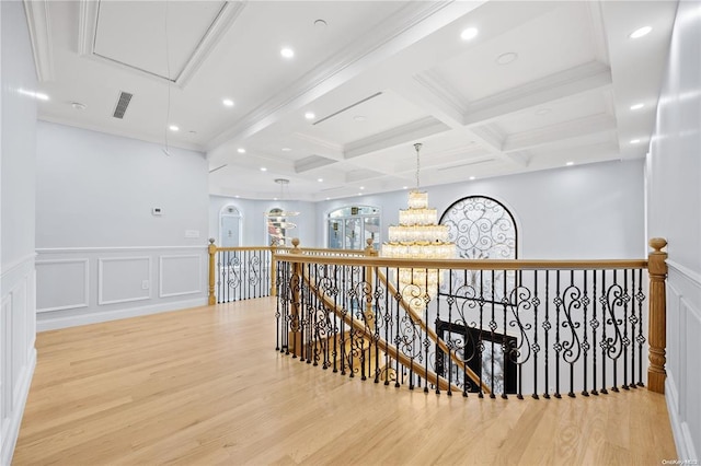 hallway with ornamental molding, coffered ceiling, beam ceiling, and light hardwood / wood-style floors