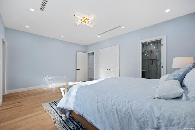 bedroom with ensuite bathroom and light hardwood / wood-style flooring