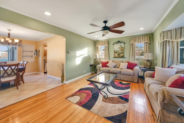 living room with crown molding, ceiling fan with notable chandelier, and light hardwood / wood-style flooring