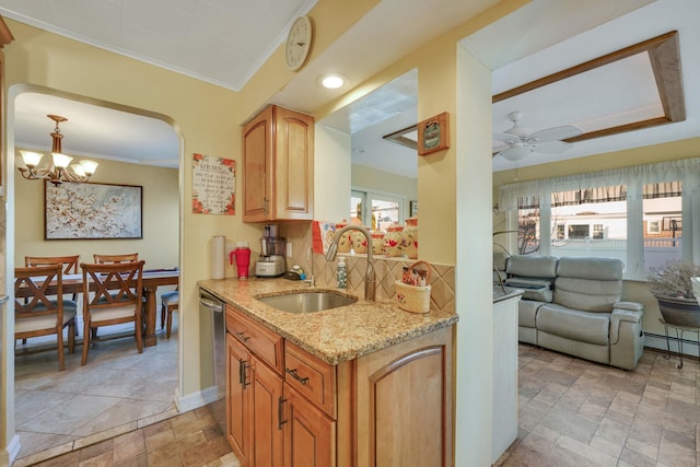 kitchen with sink, backsplash, light stone counters, ornamental molding, and decorative light fixtures