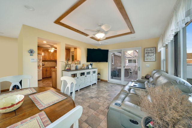 dining space featuring a raised ceiling and ceiling fan