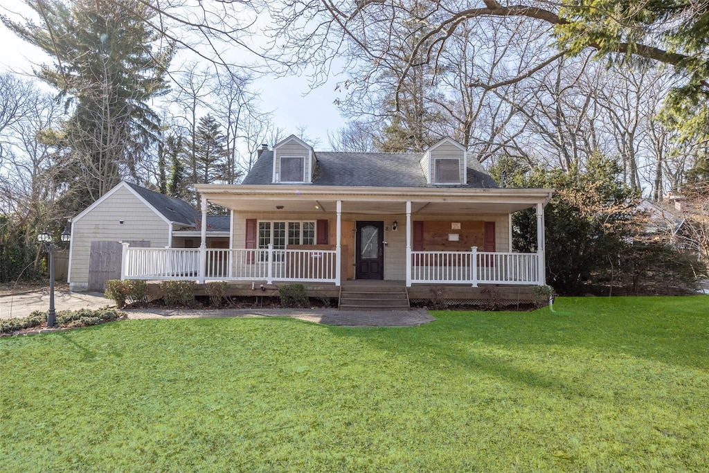 new england style home featuring covered porch and a front lawn