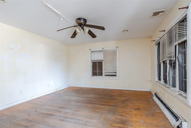 empty room with ceiling fan, wood-type flooring, and a baseboard heating unit