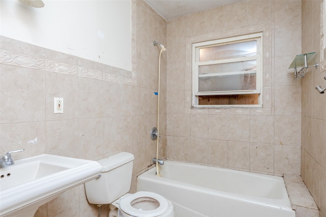 full bathroom with tiled shower / bath combo, sink, tile walls, and toilet