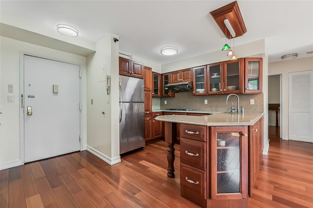 kitchen featuring backsplash, stainless steel appliances, light stone countertops, dark hardwood / wood-style flooring, and decorative light fixtures