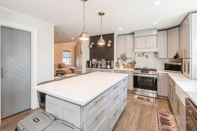 kitchen with a kitchen island, decorative backsplash, hanging light fixtures, light hardwood / wood-style floors, and stainless steel appliances