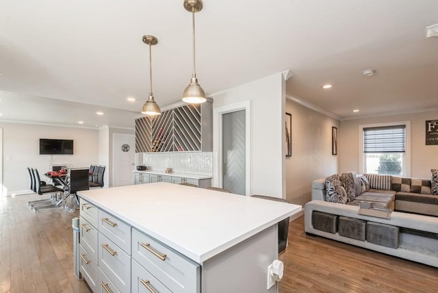 kitchen featuring pendant lighting, crown molding, light hardwood / wood-style flooring, tasteful backsplash, and a kitchen island