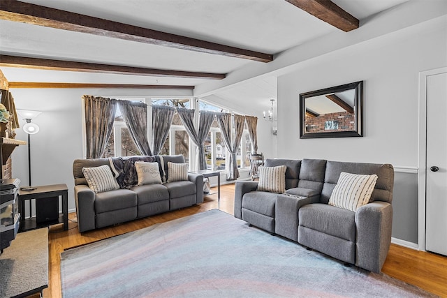 living area featuring vaulted ceiling with beams, a notable chandelier, baseboards, and wood finished floors