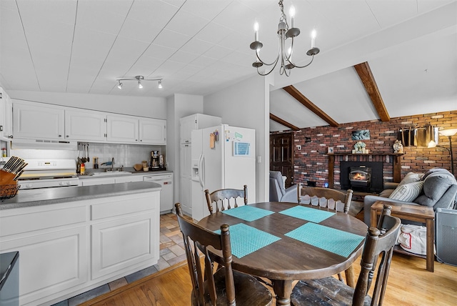 dining area with lofted ceiling with beams, brick wall, light wood finished floors, a wood stove, and an inviting chandelier