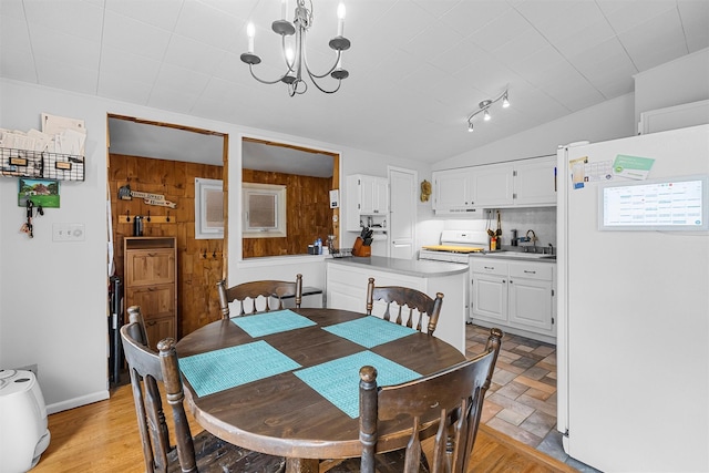 dining room with wood walls, vaulted ceiling, and a notable chandelier