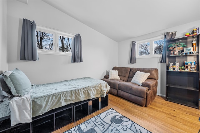 bedroom featuring lofted ceiling, multiple windows, and light wood-style flooring