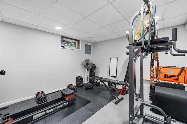 exercise area with a paneled ceiling, electric panel, and baseboards