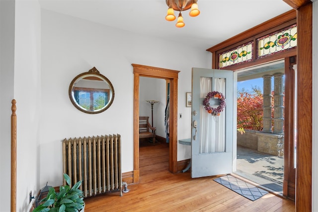 foyer entrance featuring a chandelier, radiator, and light wood-type flooring