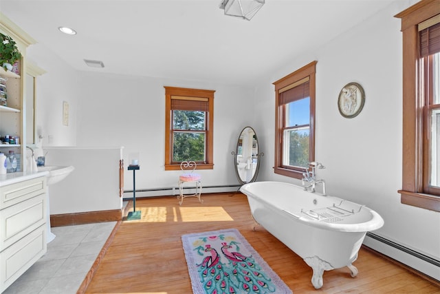 bathroom featuring vanity, a baseboard heating unit, hardwood / wood-style floors, and a bath