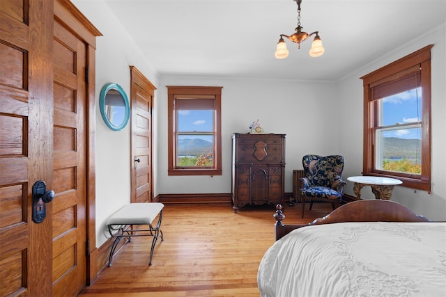 bedroom featuring ornamental molding, a notable chandelier, and light wood-type flooring