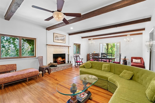 living room with beamed ceiling, ceiling fan with notable chandelier, hardwood / wood-style floors, and a fireplace