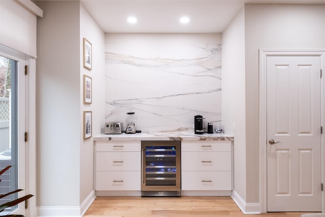 bar with white cabinetry, backsplash, beverage cooler, and light hardwood / wood-style floors