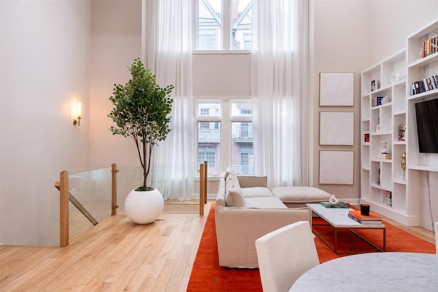 sitting room with hardwood / wood-style flooring, a towering ceiling, and a wealth of natural light