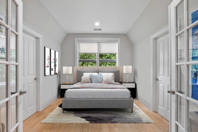 bedroom featuring lofted ceiling, light hardwood / wood-style floors, and french doors