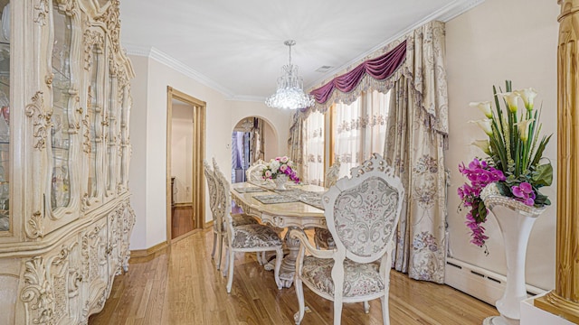 dining area featuring arched walkways, light wood finished floors, an inviting chandelier, ornamental molding, and a baseboard heating unit