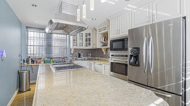 kitchen featuring glass insert cabinets, island range hood, stainless steel appliances, white cabinets, and decorative light fixtures