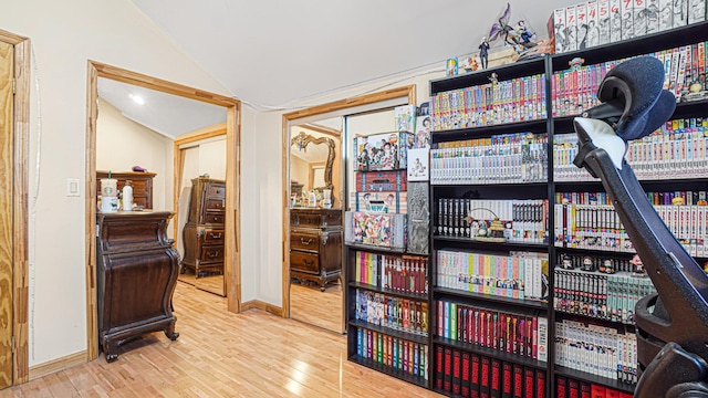 hallway with lofted ceiling, baseboards, and wood finished floors