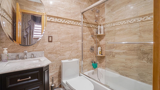 bathroom featuring toilet, enclosed tub / shower combo, tile walls, and vanity