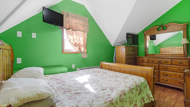 bedroom with lofted ceiling, a baseboard heating unit, and wood finished floors