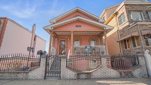 view of front of home with covered porch, a fenced front yard, and a gate