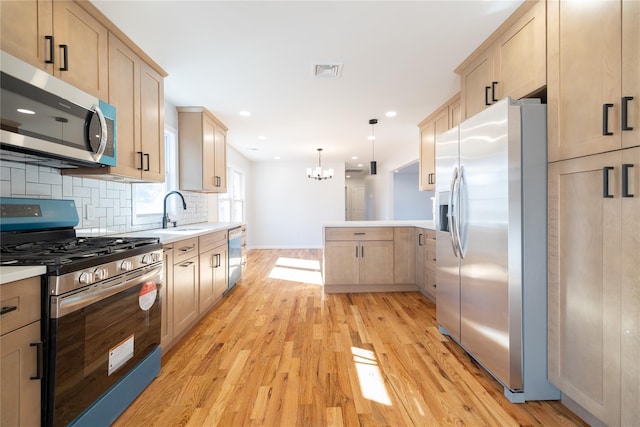 kitchen featuring stainless steel appliances, decorative light fixtures, sink, and light brown cabinets