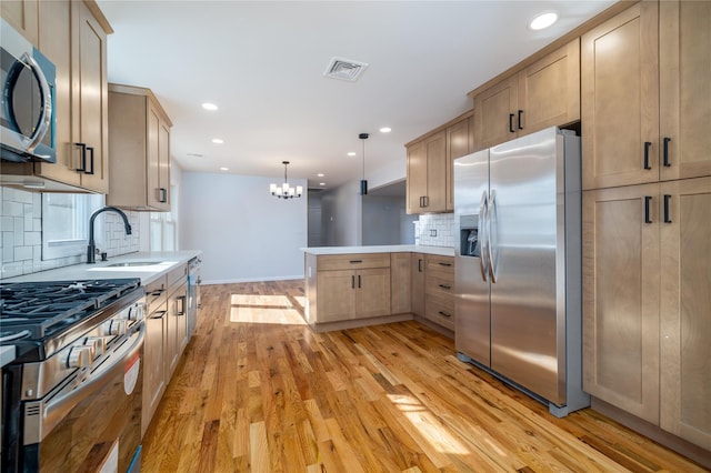 kitchen featuring sink, hanging light fixtures, kitchen peninsula, stainless steel appliances, and light wood-type flooring