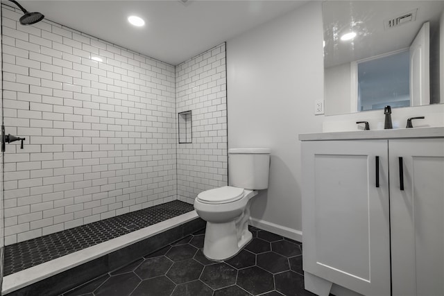 bathroom with vanity, a tile shower, tile patterned floors, and toilet