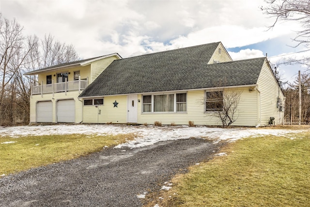 front of property with a garage, a front lawn, and a balcony