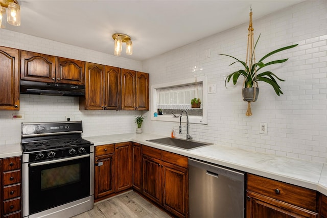 kitchen featuring black range with gas stovetop, dishwasher, sink, and decorative backsplash