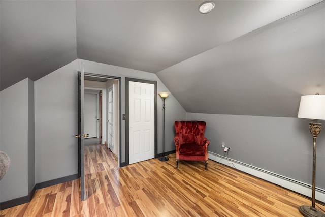 sitting room with a baseboard heating unit, light hardwood / wood-style flooring, and vaulted ceiling