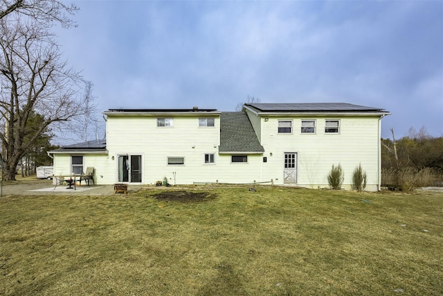 back of house featuring a yard, a patio area, and solar panels